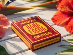 A hybrid poker deck, limited edition featuring tropical flowers in the background on a white table, and showing some key face cards for the hawaiian sakura game of hanafuda. This is a closeup